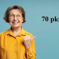 Uśmiechnięta starsza kobieta w okularach i żółtej bluzce wskazuje kciukiem na napis "70 pkt".