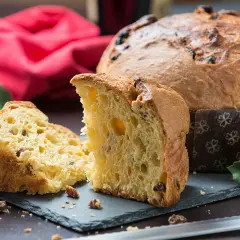 Un delicioso panettone, un dulce navideño italiano, cortado en rebanadas, con pasas y frutas confitadas.