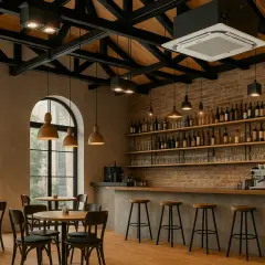 Interior de un bar con mesas, sillas, barra, estanterías llenas de botellas y un aire acondicionado en el techo, creando un ambiente de local climatizado.