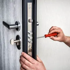 Maintenant, on ajuste le pêne porte avec un tournevis. La serrure de sécurité est en cours d'installation sur la porte grise.