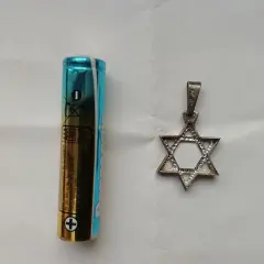 Obok baterii AAA leży srebrny wisiorek w kształcie Gwiazdy Dawida. To symbol, co oznacza przynależność i tożsamość.