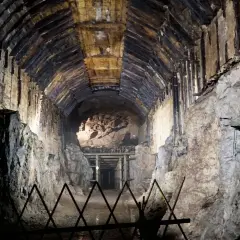 Mroczny tunel kopalni w **Przytkowicach**, z drewnianym stropem i kamiennymi ścianami, prowadzi w głąb ziemi.