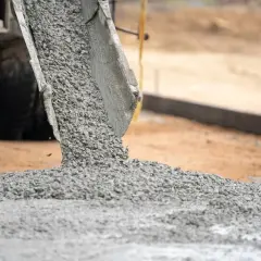 Gruszka betonu z betoniarki wysypuje się na plac budowy. Trudno ocenić ile m3 betonu jest wylewane.