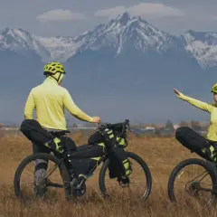 Para wyprawy rowerowej w górach. Widać rowery z sakwami, co zabrać na wyprawę rowerową, i ludzi w żółtych kurtkach.