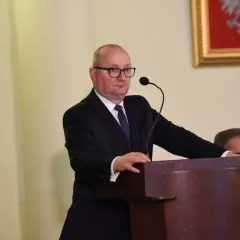 Mężczyzna w garniturze przemawia przy mównicy.