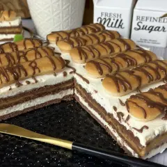 Pyszne ciasto z kajmakiem i mascarpone, udekorowane biszkoptami i czekoladą. Idealne na deser.
