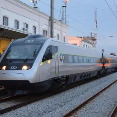 Tren moderno plateado y otro amarillo en estación, listos para el viaje de Lisboa a Oporto.