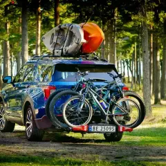 Gotowi na przygodę! Błękitny SUV z rowerami na bagażniku i kajakami na dachu, idealny na pętlę bieszczadzką.