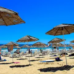 Słoneczna plaża w Bułgarii, pełna leżaków i parasoli. Ludzie odpoczywają, ciesząc się wakacjami. Czy w Bułgarii jest bezpiecznie? Tak, to popularny i bezpieczny kierunek turystyczny.