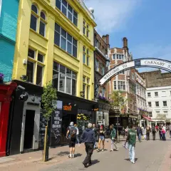 Kolorowe fasady sklepów i łuk z napisem "Welcome to Carnaby Street" zapraszają do tętniącej życiem ulicy pełnej ludzi.