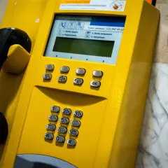 Żółta budka telefoniczna z numerem kierunkowy 94. Słuchawka czeka na połączenie.