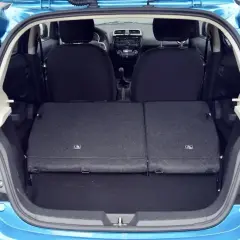 Błękitny Mitsubishi Space Star z otwartym bagażnikiem. Widoczne złożone tylne siedzenia, tworzące płaską przestrzeń ładunkową.
