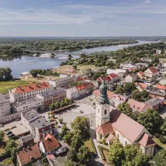 Widok z lotu ptaka na miasto z rzeką i mostem. W centrum plac z kościołem, a w oddali widać zabudowania i las. Na jednym z budynków widoczny napis "Fordon".