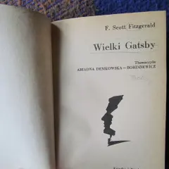 Strona tytułowa "Wielkiego Gatsby'ego" F. Scotta Fitzgeralda. Czarno-biała grafika profilu twarzy.