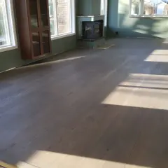 Ett rum med mörkt parkettgolv som behandlas utan slipning. Solstrålar lyser upp golvet.