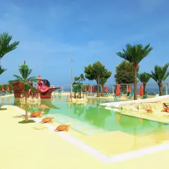 Villaggi Marche sul mare per bambini: piscina con nave pirata, palme e tartarughe. Ideale per vacanze spensierate.