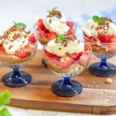 Fyra glas med jordgubbar, grädde och chokladsmulor. En härlig somrig dessert som ser otroligt god ut!