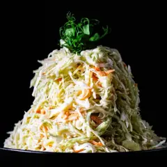 Ein Berg aus Krautsalat mit Karotten, verfeinert mit cremigem coleslaw dressing, gekrönt von grünen Sprossen.