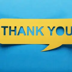 Un fumetto giallo ritagliato con la scritta "THANK YOU" su sfondo blu. Un modo per dire "prego" o "di niente" quando qualcuno ti ringrazia.