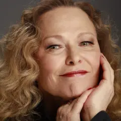 Portret Edyty Geppert, artystki znanej z poruszających utworów. Jej spojrzenie i gest dłoni przy policzku sugerują głębię emocji, które odzwierciedlają jej piosenki.