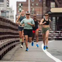 Grupa biegaczy na moście, wykonująca trening fartlek. Dynamiczne tempo i skupienie na osiągnięciu celu.