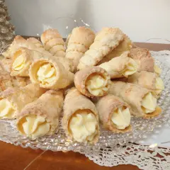 Pyszne ciasto na rurki z kremem, ułożone na talerzu, ozdobione światełkami.