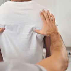 Fizjoterapeuta bada plecy pacjenta, szukając przyczyn bólu żeber, który może być związany ze zwyrodnieniem kręgosłupa.