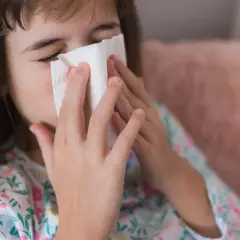 Dziewczynka z chusteczką przy nosie, być może potrzebuje antybiotyku na zatoki.