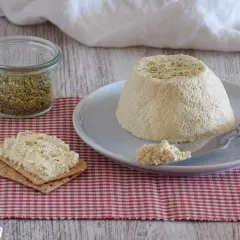 Deliciosa ricotta vegana con hierbas, servida en un plato con galletas y limón.