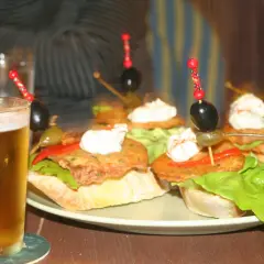 Små munsbitar med oliver och krämig topping, en perfekt start på en kväll med san sebastian mat. Ett glas öl bredvid.