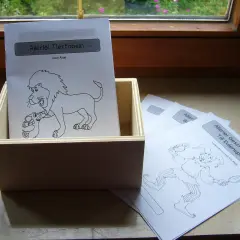 Holzkiste mit Blättern für fabeln zum lesen. Ein Blatt zeigt einen Löwen mit einem Lamm, ein anderes einen Till Eulenspiegel.