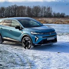 Niebieski Renault Symbioz zaparkowany na zaśnieżonej polanie nad zamarzniętą rzeką.