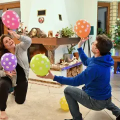 Wesołe pomysły na gry w domu: para bawi się balonami w salonie przy choince.