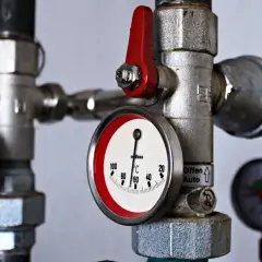 Compteur calorifique sur tuyauterie avec thermomètre indiquant 60°C. Vannes rouges et manomètres visibles.