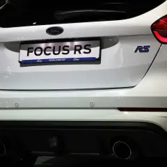 Biały Ford Focus RS z niebieskim znaczkiem RS i podwójnymi końcówkami wydechu.