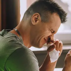 Homme éternuant, le nez sec et irrité. Il cherche un remède grand-mère pour soulager son inconfort.