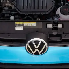 Motorutrymmet på en blå Volkswagen. En etikett visar information om olja och kylvätska, vilket kan vara relevant vid ett **volkswagen gasbil problem**.