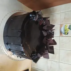Czekoladowy tort z polewą, czekoladowymi płatkami i ciasteczkami Oreo.