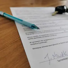 Długopis i kluczyki leżą na dokumencie, który pomoże Ci dowiedzieć się, jak spisać umowę kupna-sprzedaży samochodu.