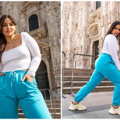 Kobieta w turkusowych dresach plus size i białej bluzce pozuje na tle katedry.