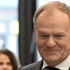 Uśmiechnięty Donald Tusk w garniturze. Ciekawe, ile Tusk ma emerytury na rękę, gdyby ją pobierał.
