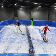 Ludzie surfują na sztucznej fali w Surf-Air, największym aquaparku w Polsce.