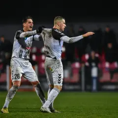 Piłkarze świętują bramkę. Jeden z nich, z numerem 26, krzyczy z radości. To zwycięstwo dla ich klubu kokosa!