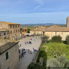 Piazza di Monteriggioni, un borgo medievale con case in pietra e un campanile. Ecco cosa vedere: un luogo incantevole da esplorare.