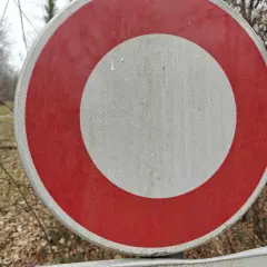 Panneau rond rouge et blanc, interdisant le passage sur un chemin forestier.