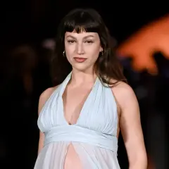Mujer con flequillo vasco y vestido vaporoso azul claro, posando con mirada directa.