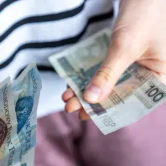 Ręce liczą banknoty 100 zł. Czy za mieszkanie komunalne się płaci? Tak, czynsz jest obowiązkowy.