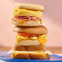 Une pile de sandwichs gourmands, parfaits pour une recette de petit-déjeuner. Œufs brouillés, fromage fondant, jambon et tomate.