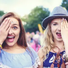 Dwie młode kobiety z brokatem na twarzy i biżuterią na rękach, zasłaniające jedno oko.