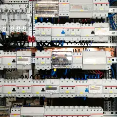 Wnętrze rozdzielni elektrycznej z licznymi wyłącznikami, bezpiecznikami i przewodami.